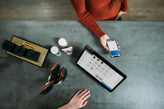 person holding smartphone beside tablet computer